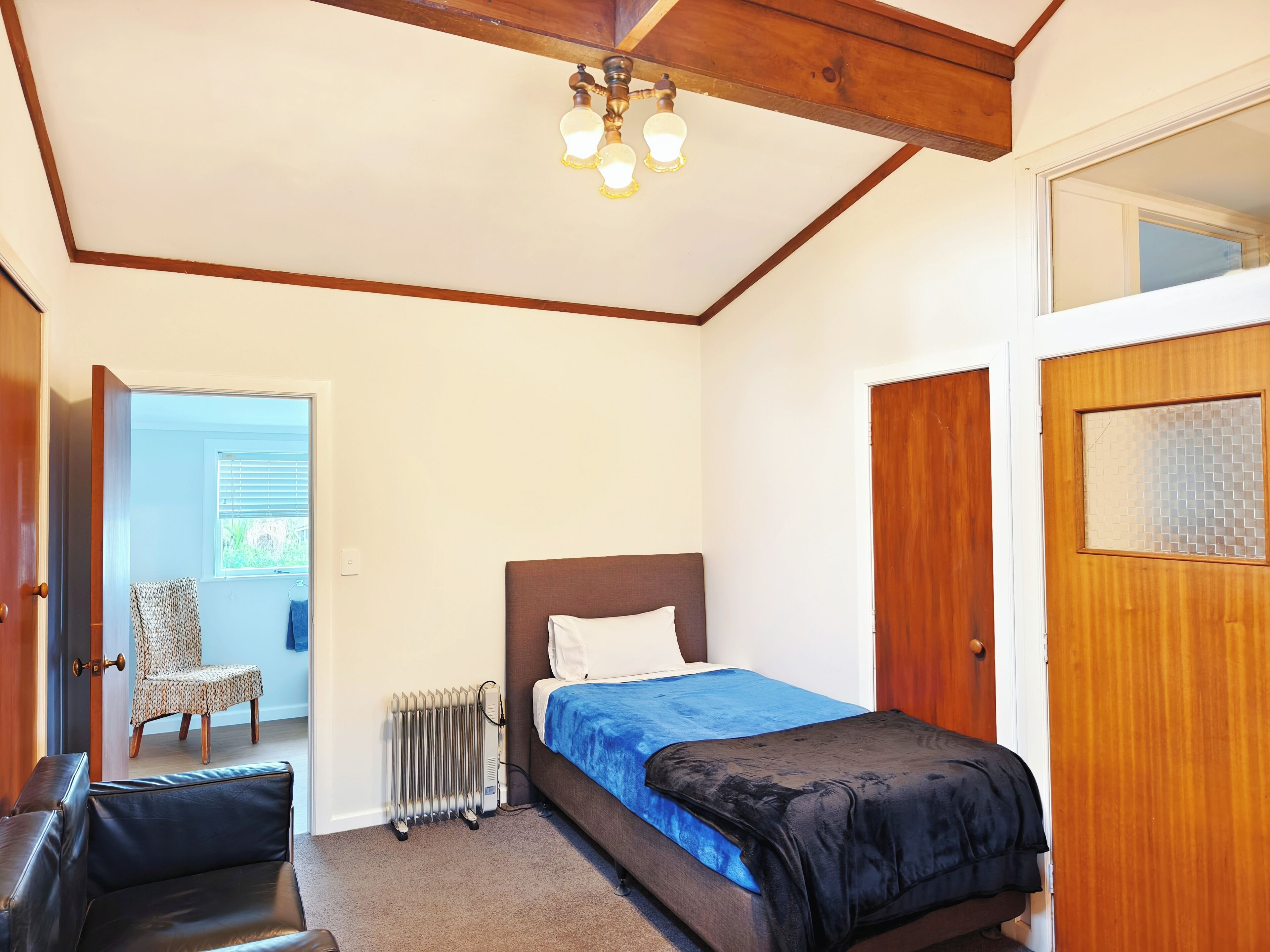 A bedroom with a bed, a radiator, a chair, and a wooden door.