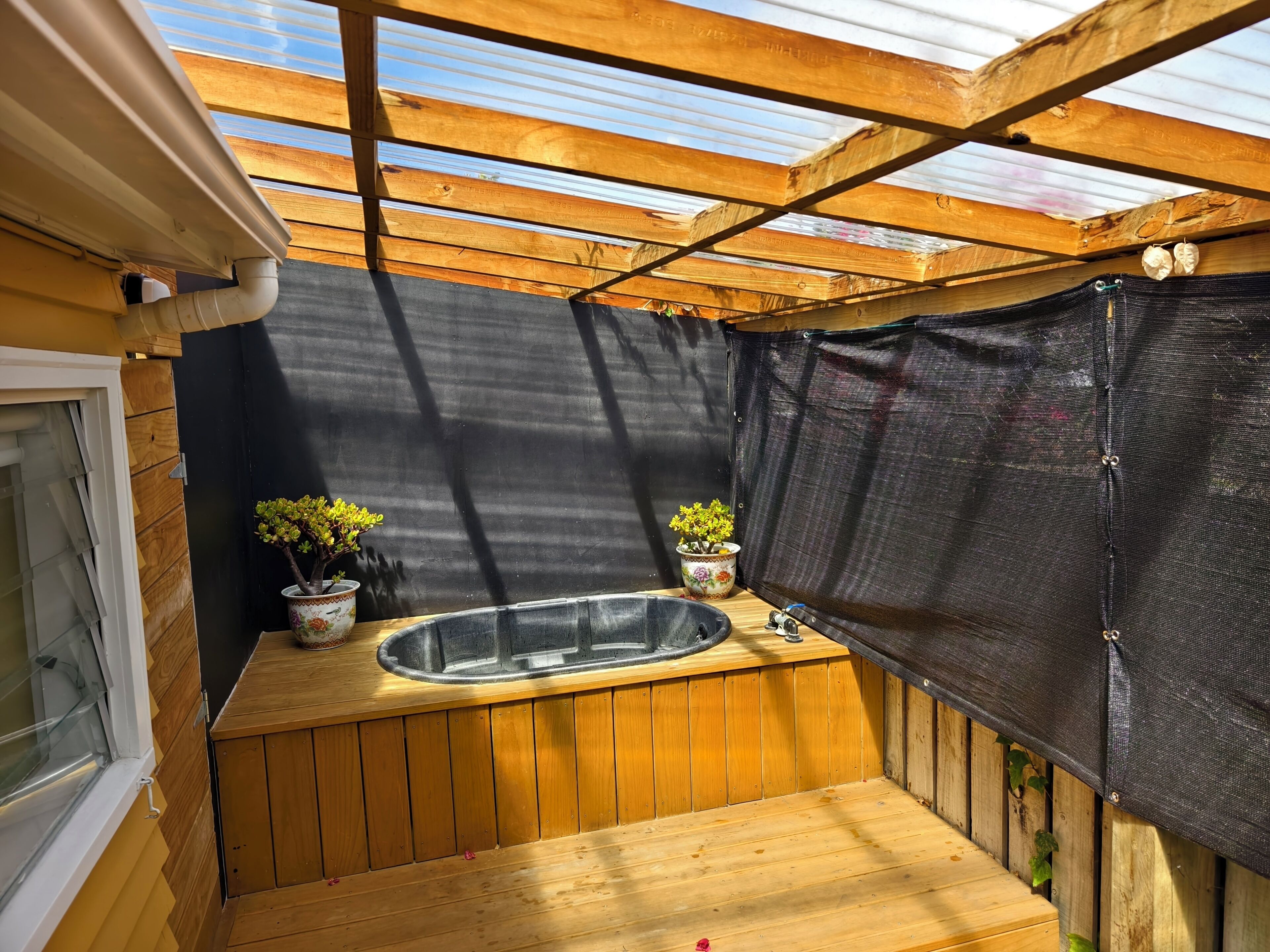 Eine Holzterrasse mit Whirlpool und zwei Blumentöpfen.