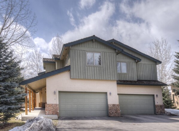 A two-story house with a garage, a covered porch, and a stone foundation. - Millers Creek Resident (Edwards)