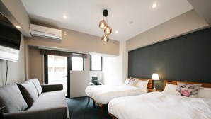 A hotel room with two beds, a sofa, a desk, and a chair. There is an air conditioning unit on the wall and a ceiling light fixture. - Zonk Hotel Nakasu (Fukuoka)