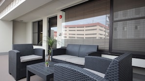 A balcony with wicker furniture, including a sofa and chairs, and a small table with a plant. - Zonk Hotel Nakasu (Fukuoka)