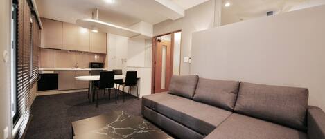 A modern living room with a sectional sofa, a marble coffee table, and a dining area with a small table and chairs.