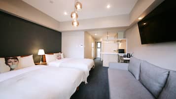 A hotel room with two beds, a sofa, a desk, and a flat-screen TV.