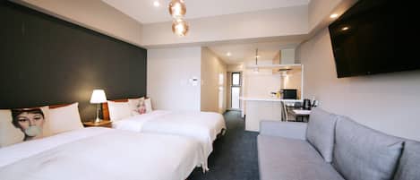 A hotel room with two beds, a sofa, a desk, and a flat-screen TV.