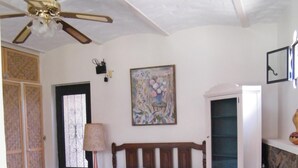 Un dormitori amb un llit, un ventilador de sostre, un quadre, un armari i una finestra.