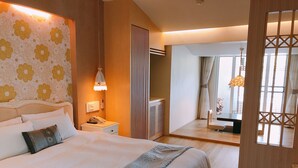 A hotel room with a large bed, bedside table, lamp, and a view of the hallway and another room through a glass door. - King's Garden Villa (Tainan)