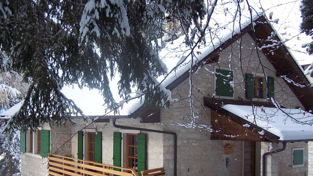 A rustic stone building with green shutters, a wooden staircase, and a snow-covered roof. - Serrada di Folgaria, the attic of Villa Gentilini (Serrada)