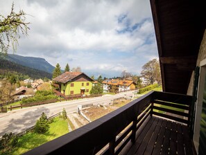 Un balcon donnant sur une route, des maisons et des montagnes.