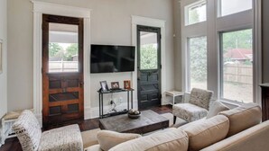 A living room with a large window, a fireplace, a television, and a sofa. - The Waverly - Less than 2mi from Downtown (Nashville)