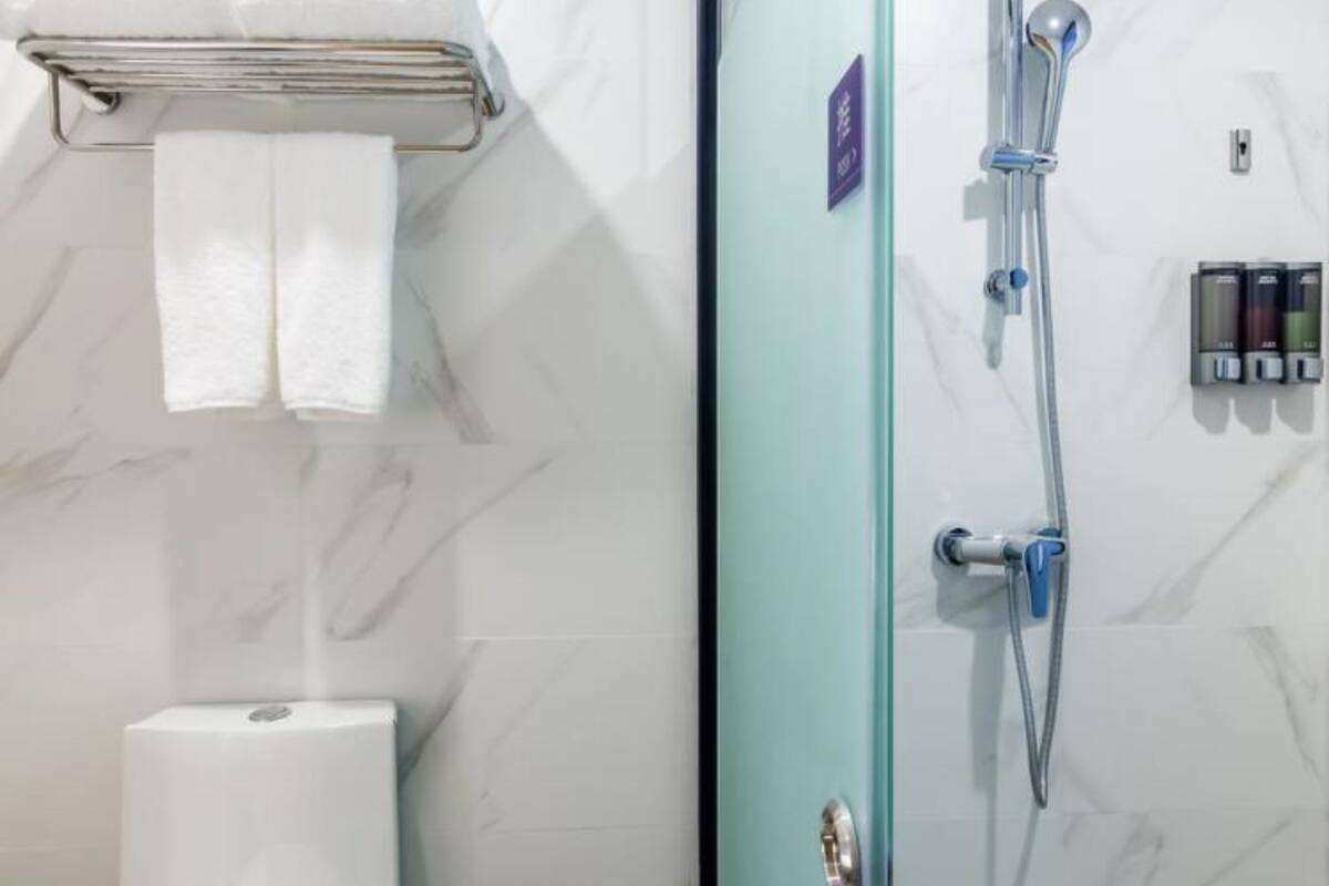 Une salle de bain comprenant des toilettes, une douche à parois de verre et un porte-serviettes avec deux serviettes.