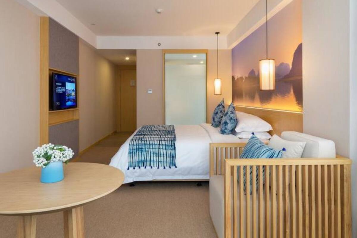 Une chambre d’hôtel comprenant un lit, un coin salon, une télévision et une œuvre d’art accrochée au mur.