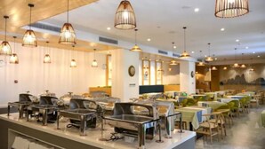 Un espace buffet doté de plusieurs points de service et éclairé par des suspensions.