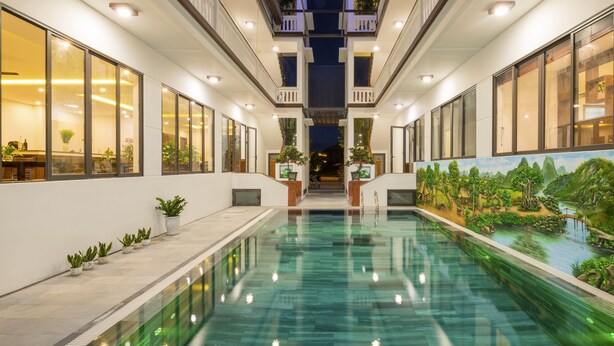 A pool area with a view of a restaurant and a mural. - Phuc Hung Riverside Villa (Da Nang)