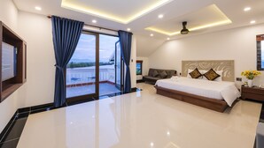 A modern bedroom with a large bed, a sofa, and a TV. - Phuc Hung Riverside Villa (Da Nang)