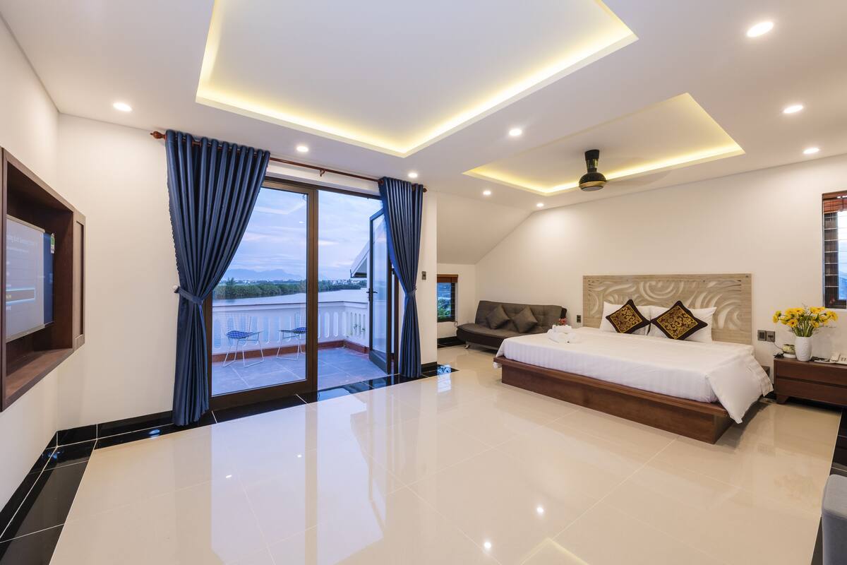 A modern bedroom with a large bed, a sofa, and a TV.