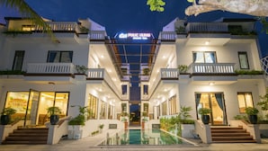 A modern hotel with a central pool, multiple balconies, and a well-lit entrance. - Phuc Hung Riverside Villa (Da Nang)