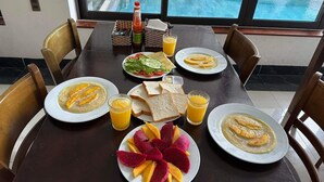 A dining table with plates of food, including soup, toast, and fruit, and glasses of orange juice. - Phuc Hung Riverside Villa (Da Nang)
