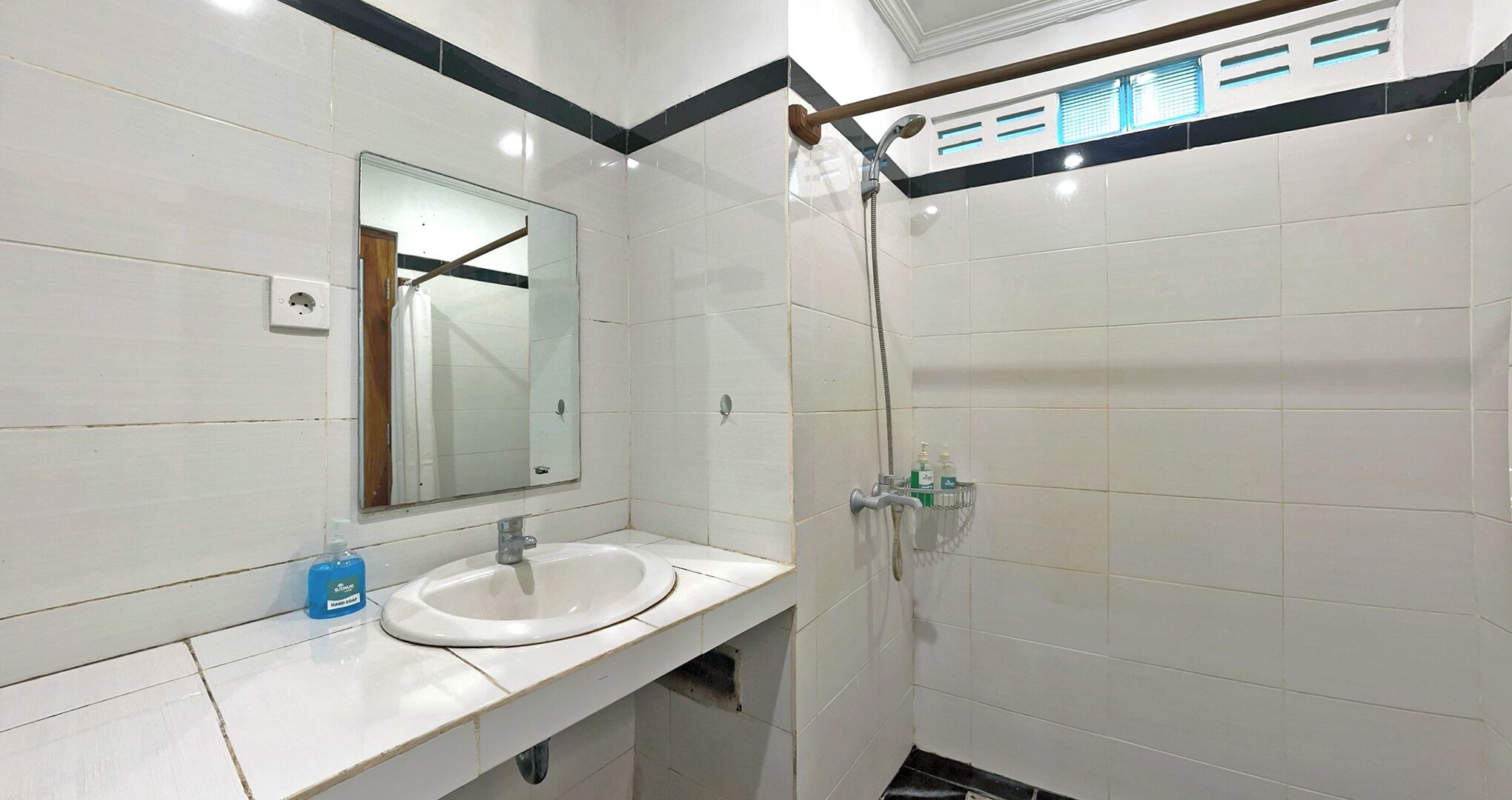 A bathroom with a white sink, mirror, and shower.