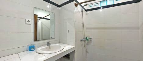 A bathroom with a white sink, mirror, and shower.