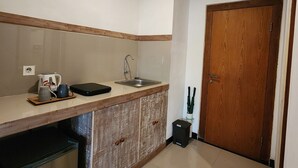 A compact kitchen with a sink, a coffee maker, and a small refrigerator. - Sanur Lodge (Denpasar)