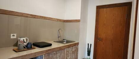 A compact kitchen with a sink, a coffee maker, and a small refrigerator.