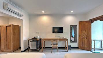 A hotel room with a bed, a desk with a chair, a TV, a wardrobe, and a door.