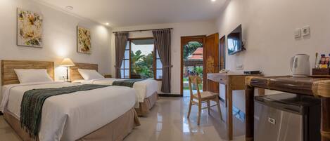 A hotel room with two beds, a desk with a kettle, a television, and a view of the outside.