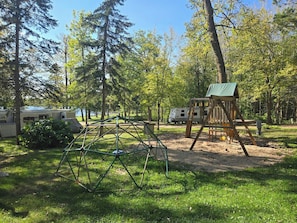 A recreational area with a swing set, a playhouse, and a small climbing structure.