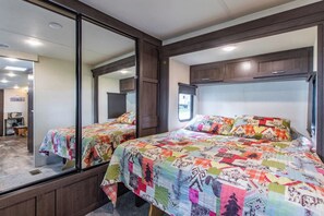 A bedroom with two beds, a large mirror, and a window.