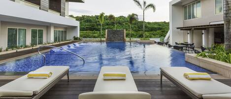 A modern pool area with lounge chairs and a stone feature in the center.