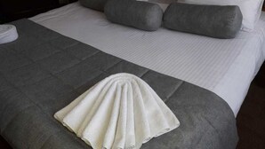 A neatly made bed with white linens, grey pillows, and a grey throw blanket. - Gostinyi Dvor Galirad (Oskemen)