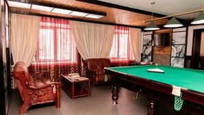 A billiards room with a pool table, leather armchairs, and a sofa. - Gostinyi Dvor Galirad (Oskemen)