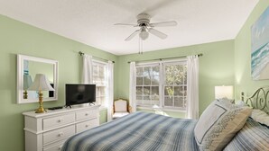 A bedroom with a bed, a dresser, a television, and a ceiling fan. - Comfortable 2 bedroom Beach Home located on quiet street (Saint Simons Island)