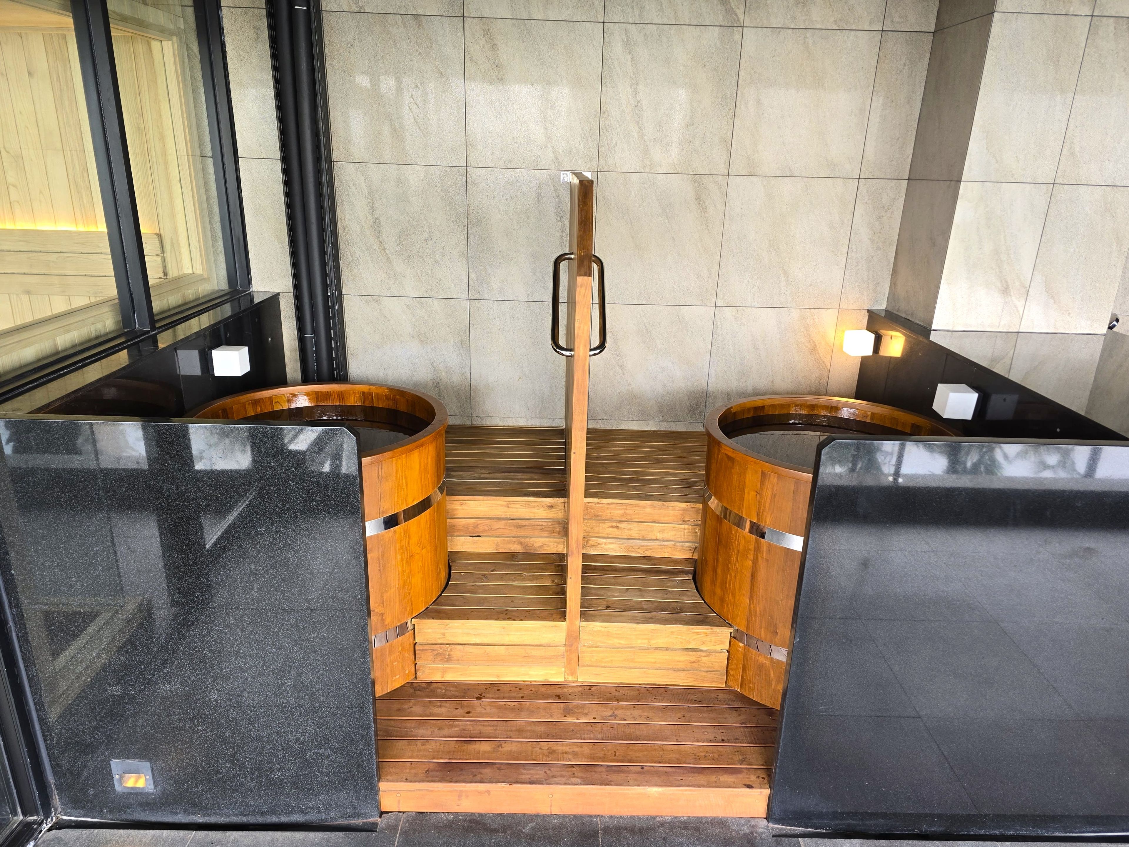 Een sauna met twee houten kuipen en een houten bank in het midden.