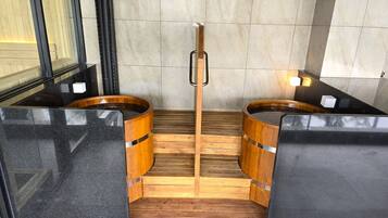 Een sauna met twee houten kuipen en een houten bank in het midden.