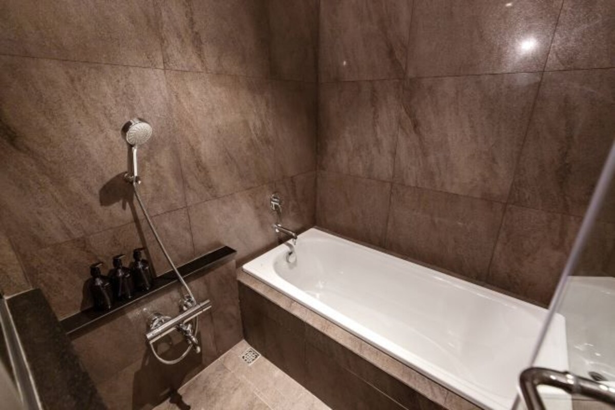 A modern bathroom with a bathtub, a shower, and a vanity with toiletries.