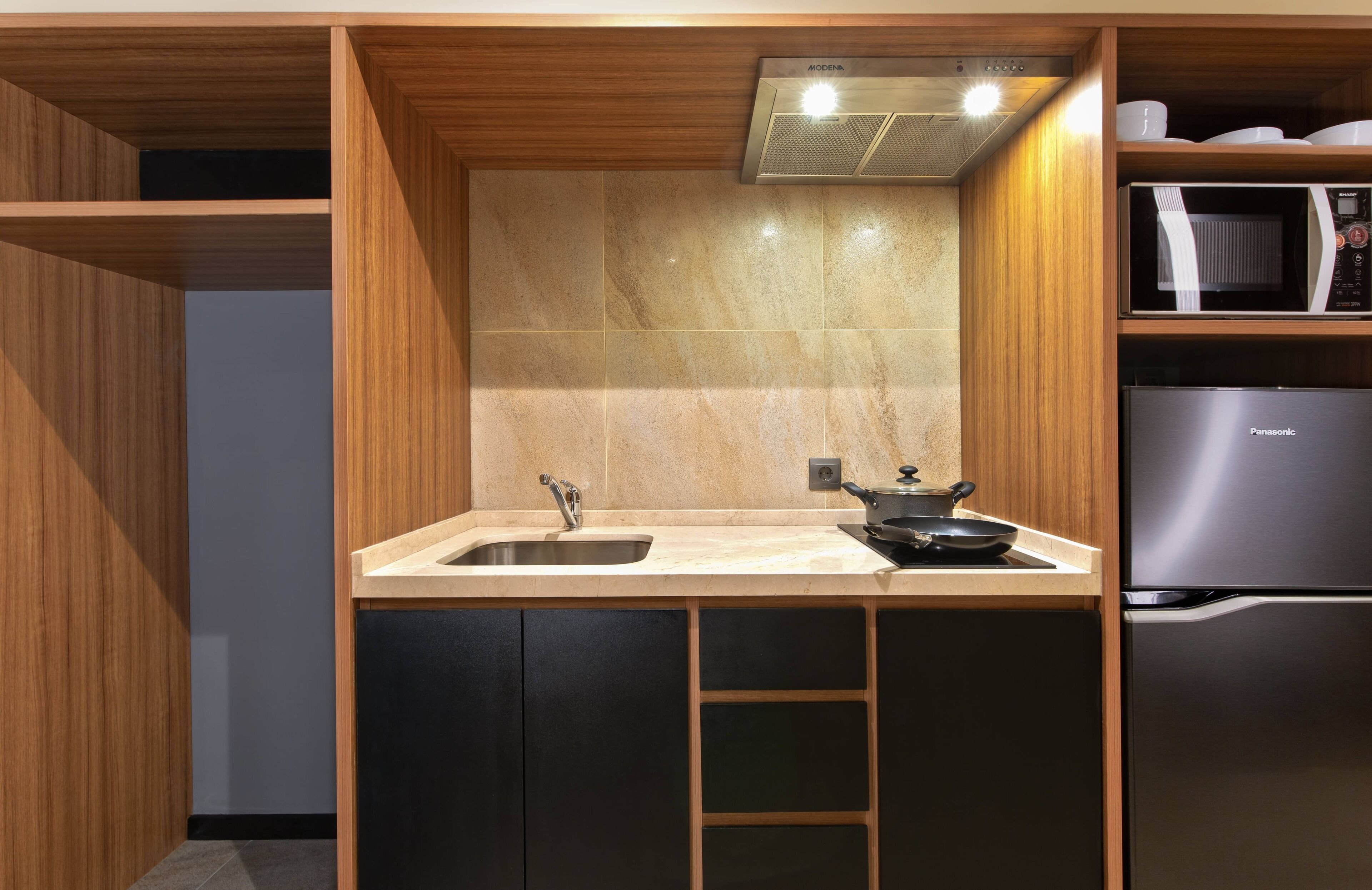 Una cocina moderna con microondas integrado, un fregadero y un refrigerador de acero inoxidable.