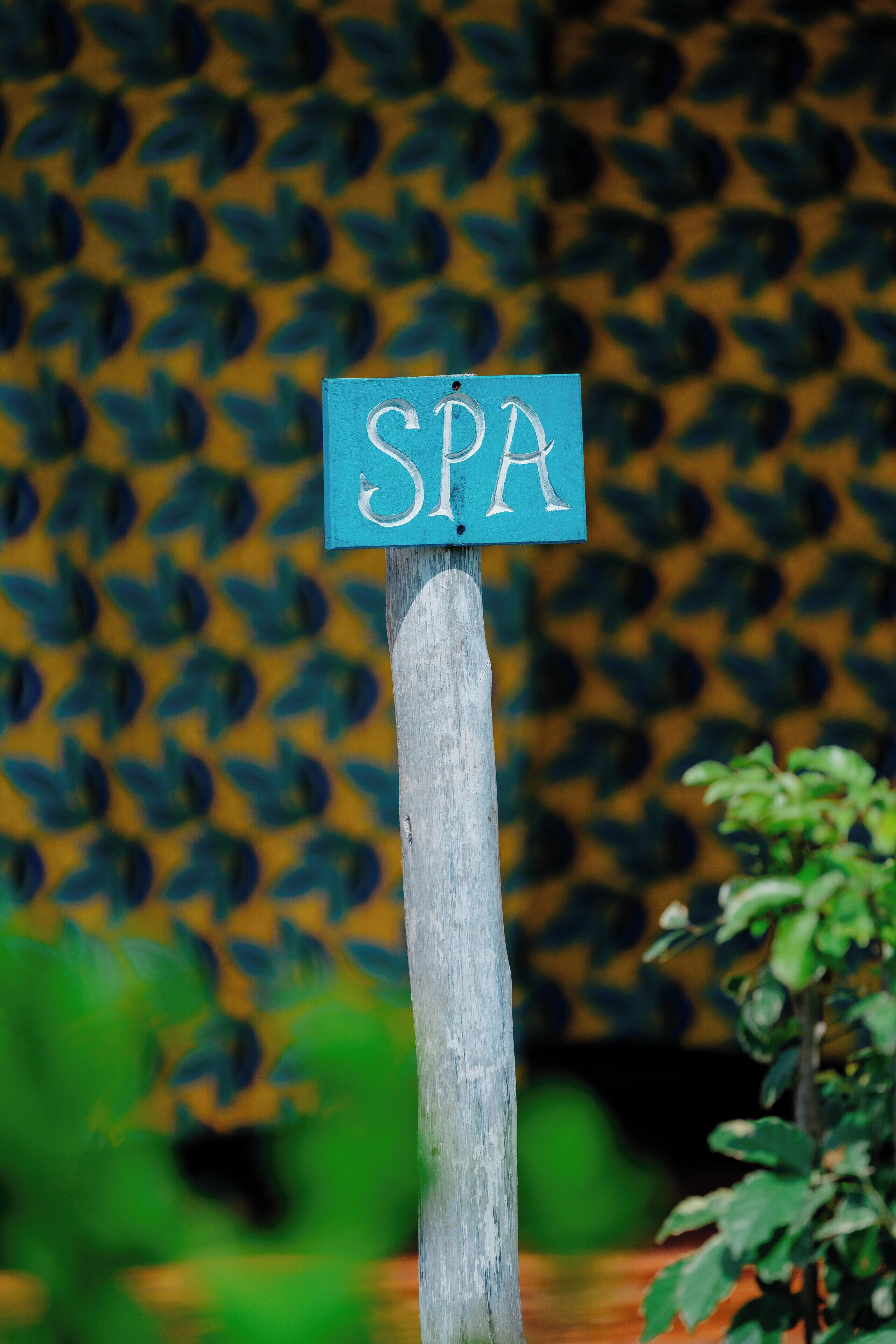 A wooden sign with the letters "SPA" on it, mounted on a post.