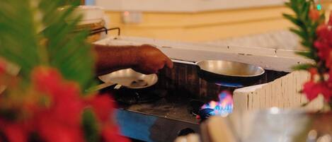 A kitchen area with a person cooking on a stove, a pot, and a bowl on the counter.