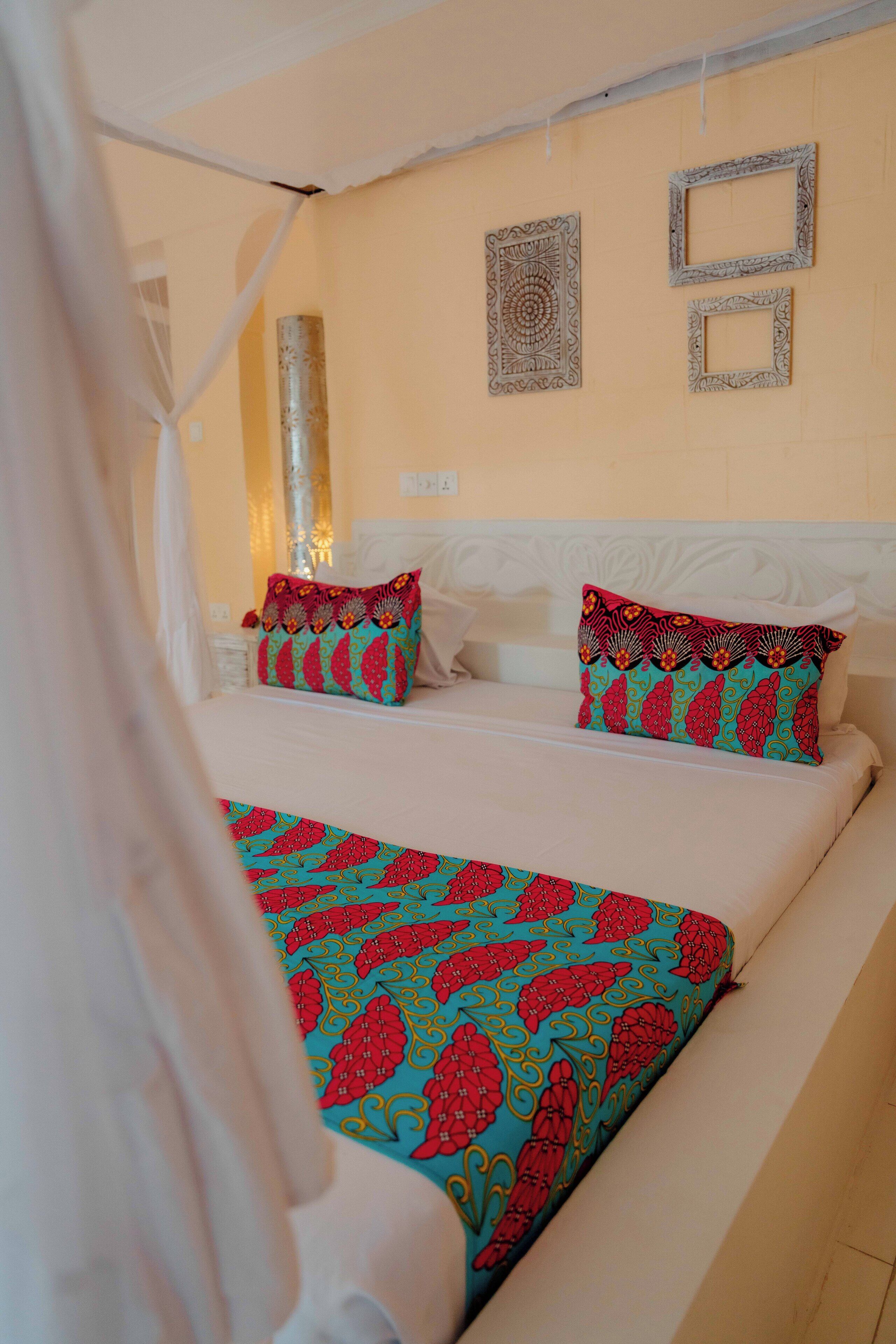 Una cama con una colcha estampada, dos almohadas y un adorno de pared.