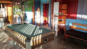 A pool table in a room with colorful walls and a wooden bench. - Salty Dog Hostel (Nias)