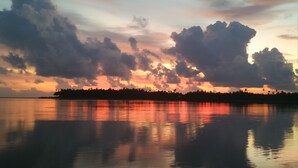 A calm lake reflecting a sunset sky with clouds. - Salty Dog Hostel (Nias)