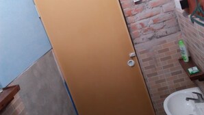 A bathroom with a toilet, sink, and a brick wall. - Salty Dog Hostel (Nias)