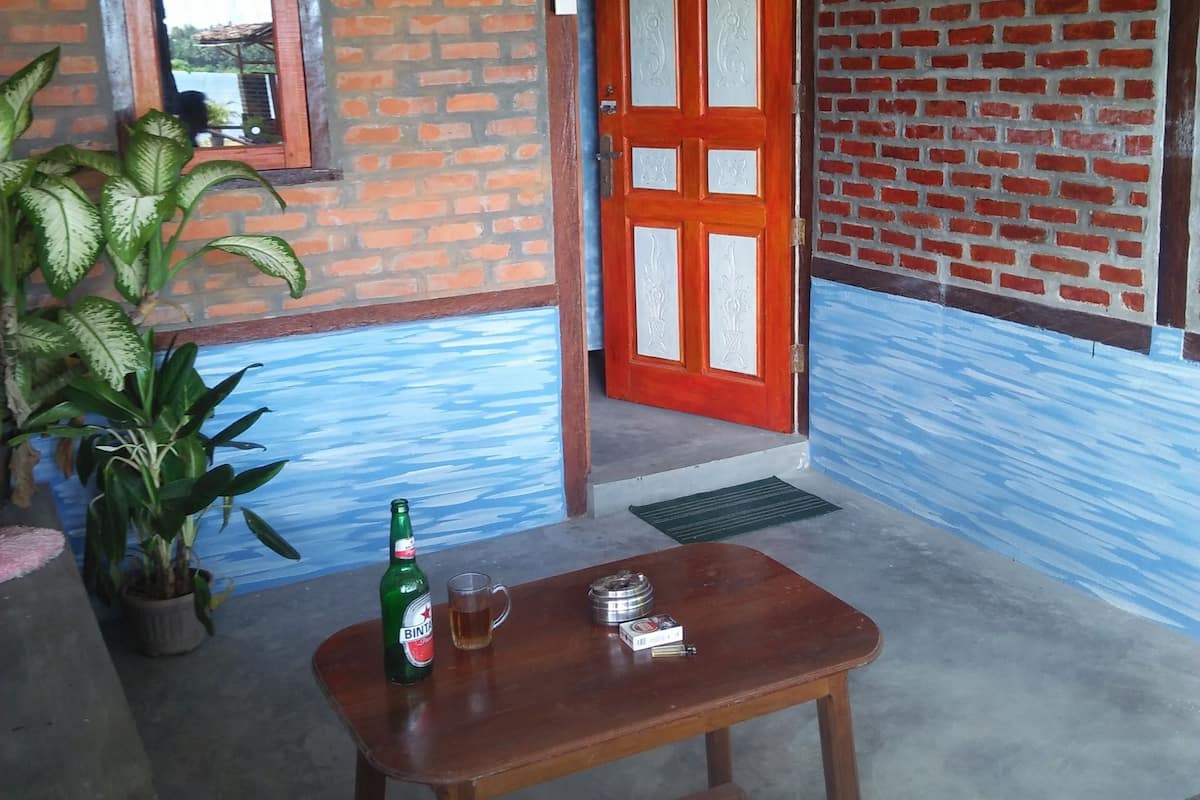 Een kamer met een bakstenen muur, een houten deur, een raam en een tafel met een fles en een kop.