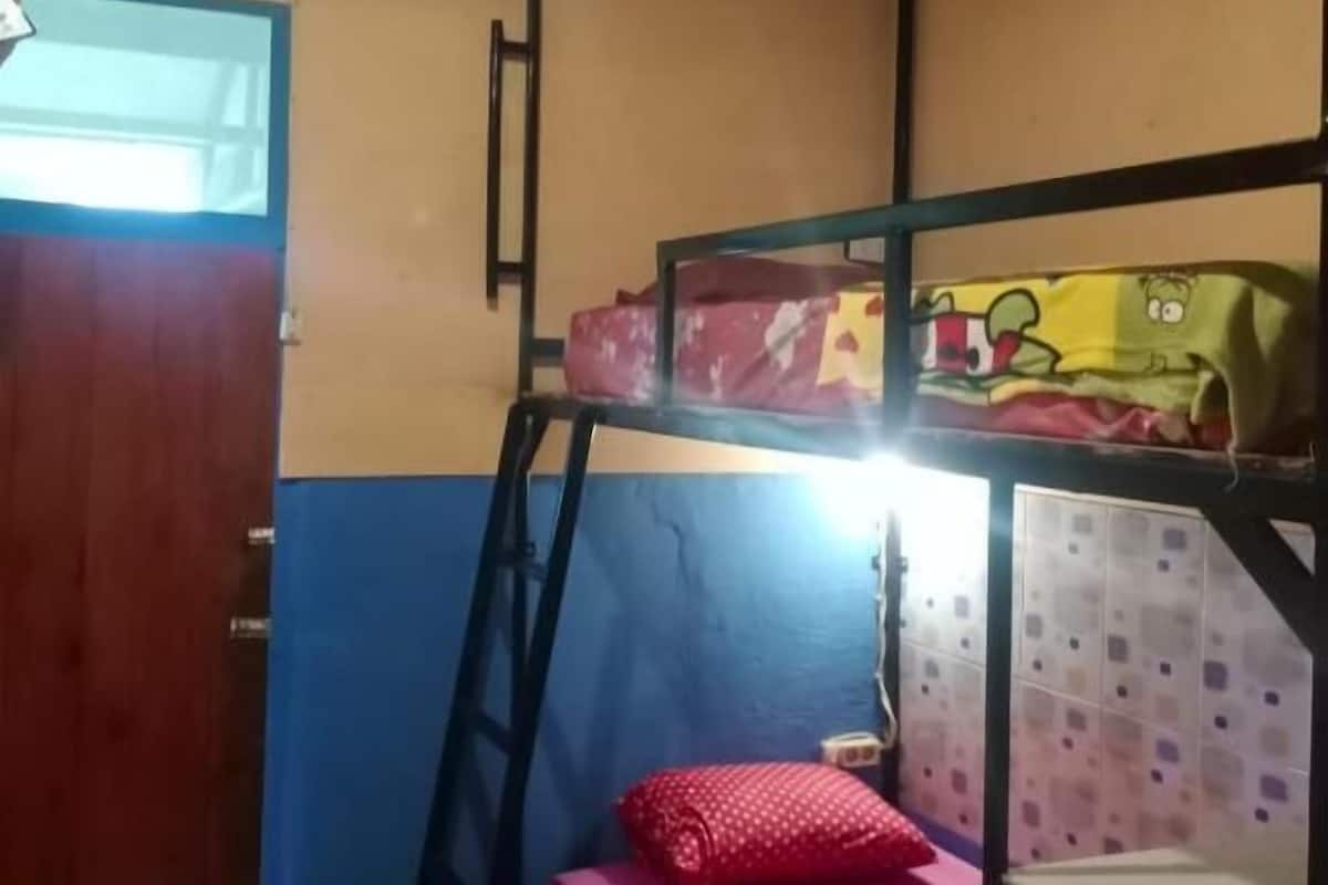 Een slaapkamer met een stapelbed, een tafeltje en een raam.