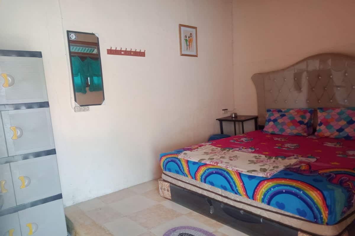 Een slaapkamer met een bed, een kledingkast, een spiegel en een tafeltje.