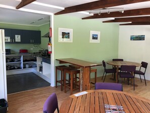 Une cuisine compacte dotée d’appareils électroménagers modernes, un coin repas avec une table en bois et des chaises violettes, et une vue sur la pièce adjacente.