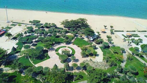 An aerial view of a coastal resort with manicured gardens, a sandy beach, and a clear view of the sea. - Ruby Luxury Hotel (Nha Trang)
