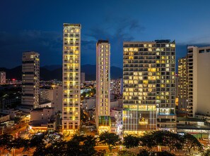 A cityscape at night with illuminated high-rise buildings, including a hotel with a prominent sign. - Ruby Luxury Hotel (Nha Trang)
