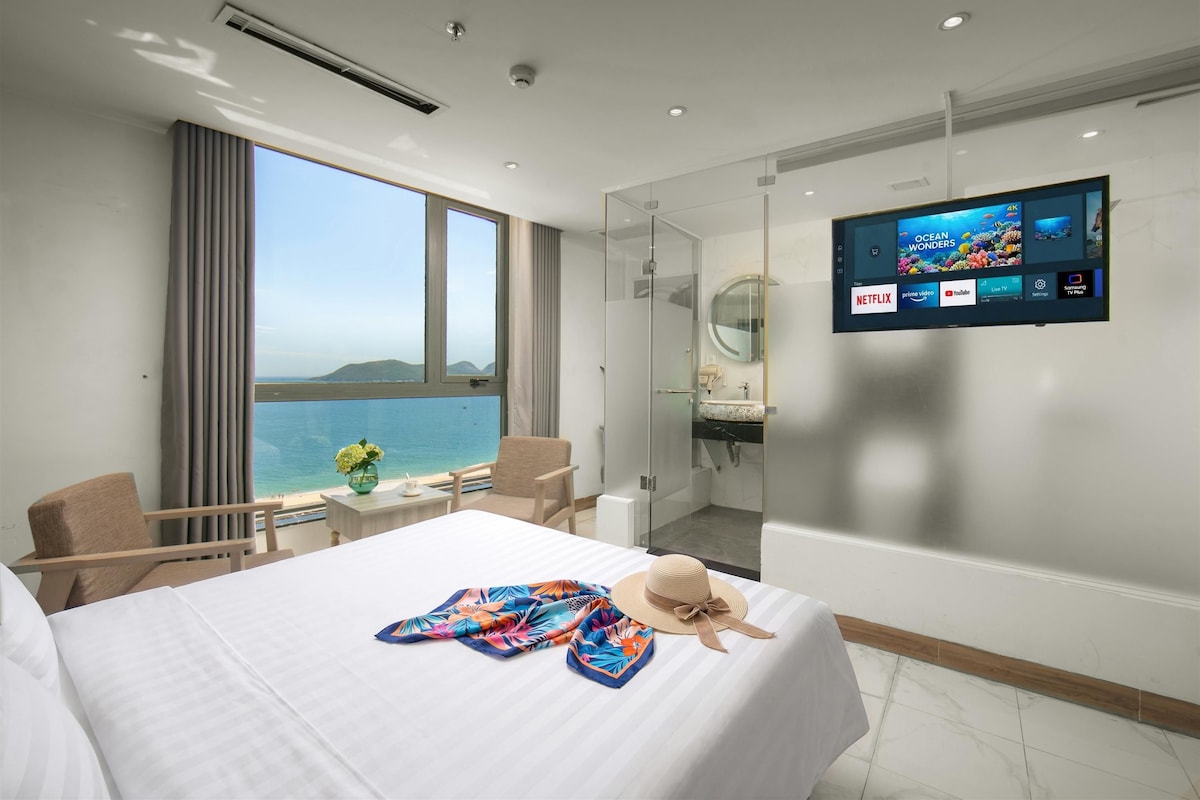 Habitació d'hotel amb llit, televisió, bany i vistes al mar.